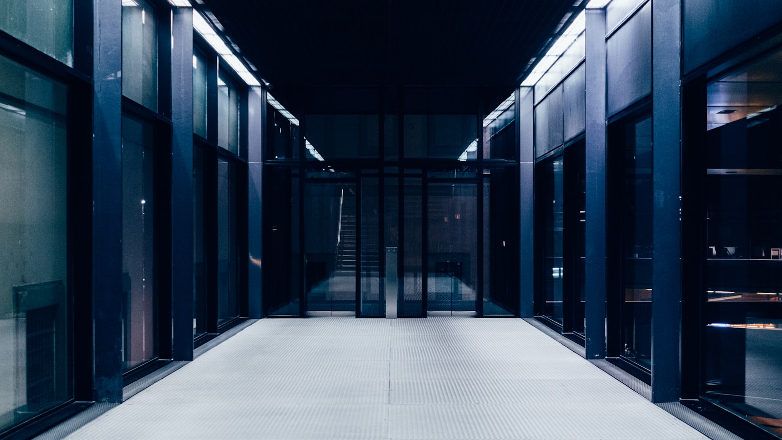 A corridor of glass doors receding toward a single lit entrance