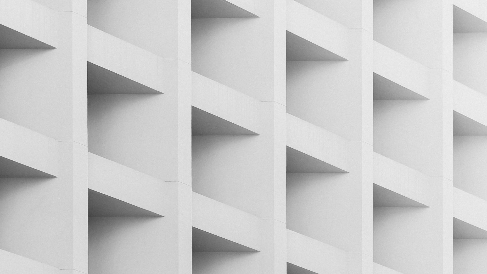 A white concrete facade of uniform repeating rectangular recesses